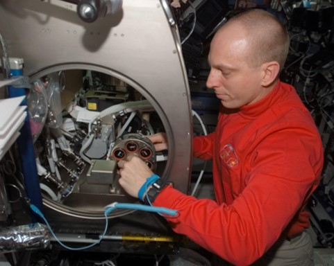 Astronaut Clay Anderson manipulating an electroplated SLA carousel in micro-gravity glovebox on ISS